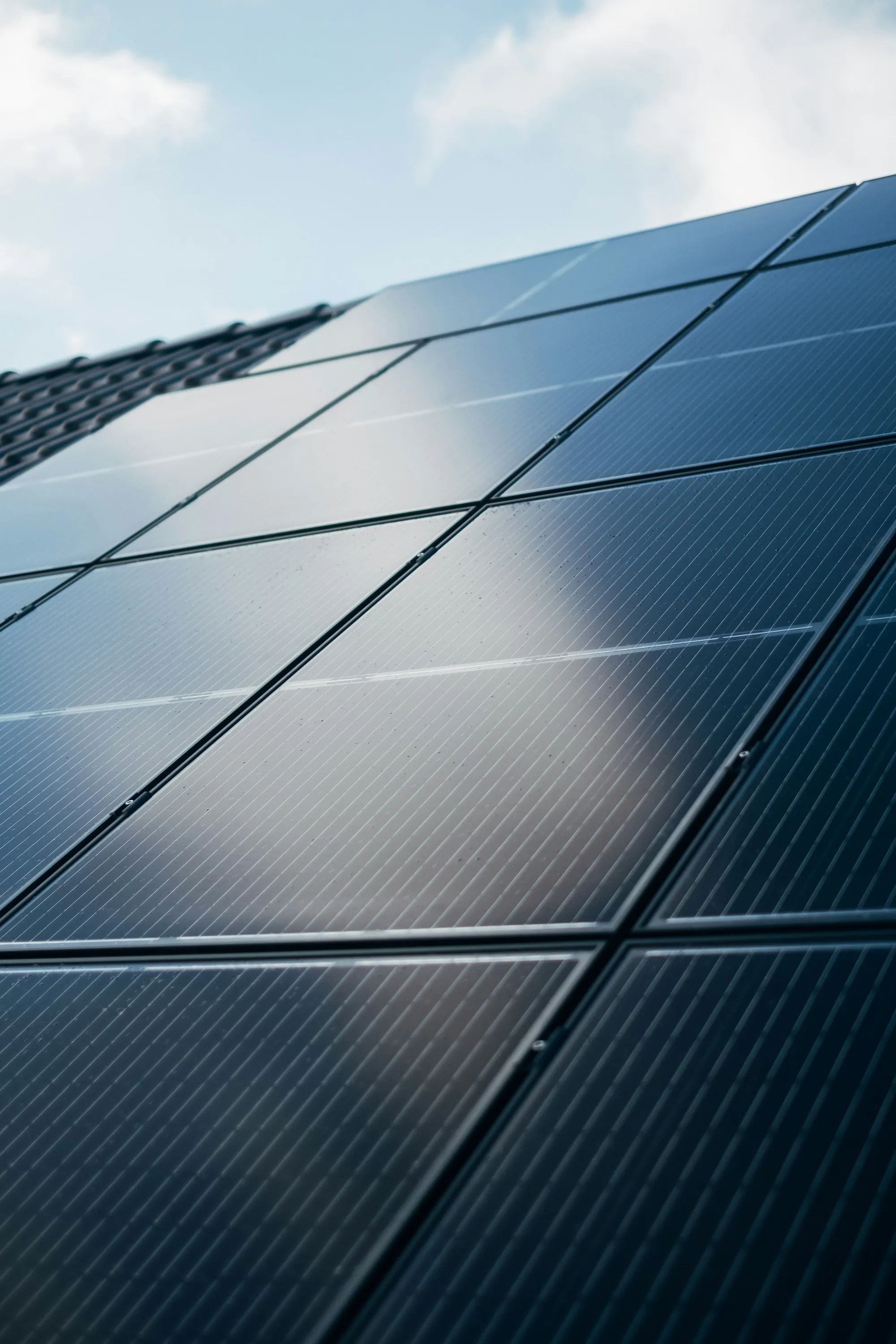 Close-up of black solar panel cells with light reflecting off the glass