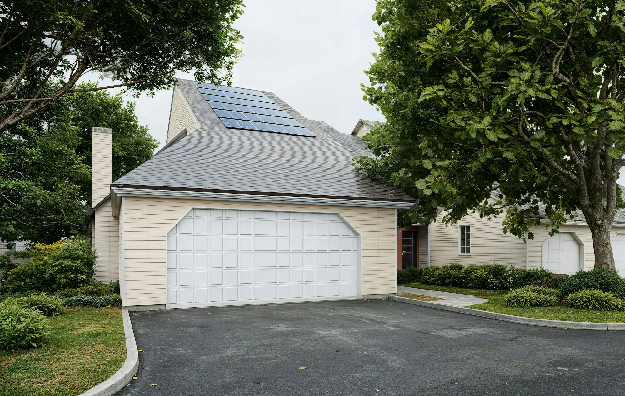Solar panels on the gray shingle roof above a white two-car garage