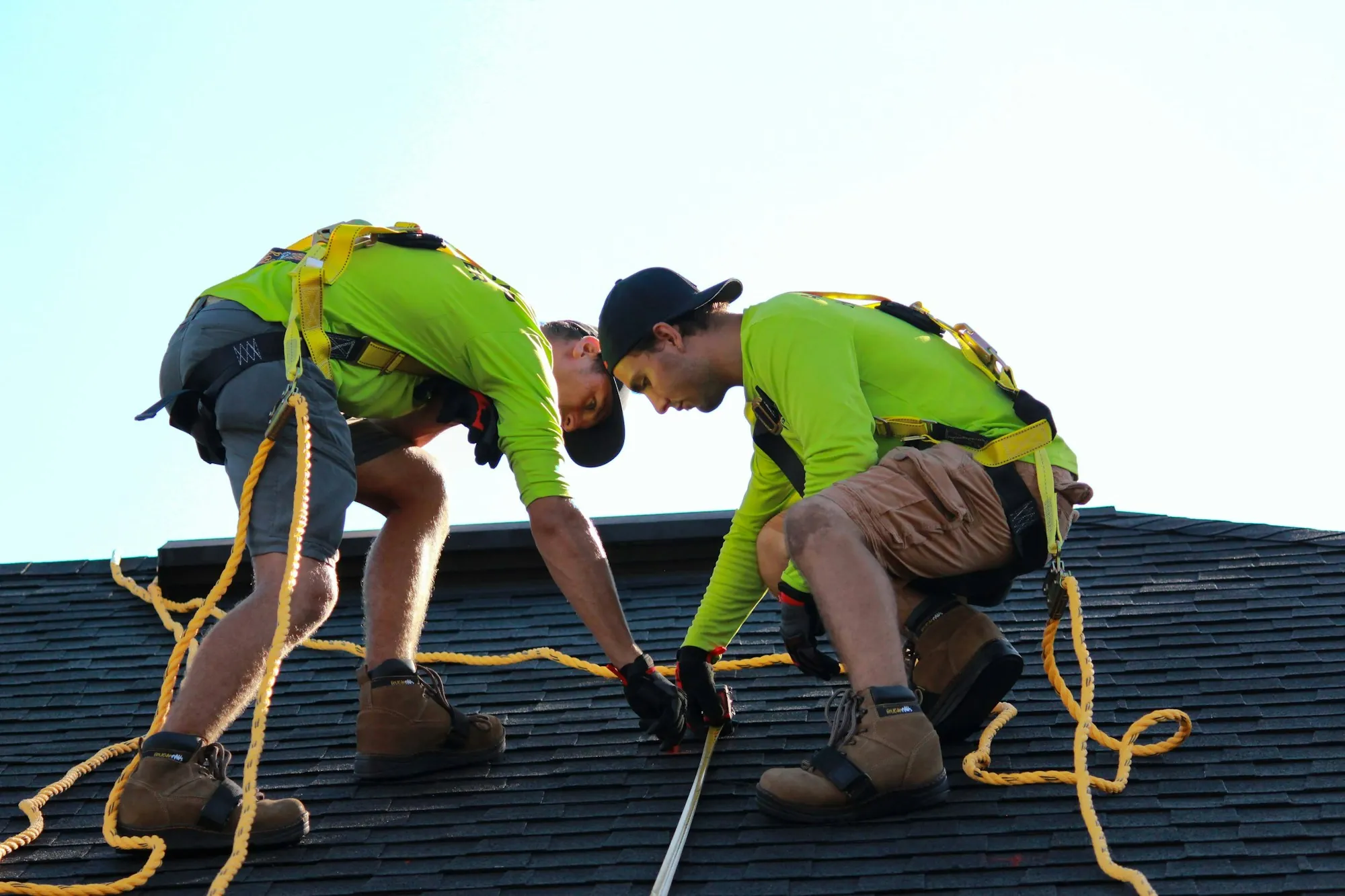 Two roofers in harnesses marking a shingle roof, the kind of crew roofing around solar panels in Palos Park